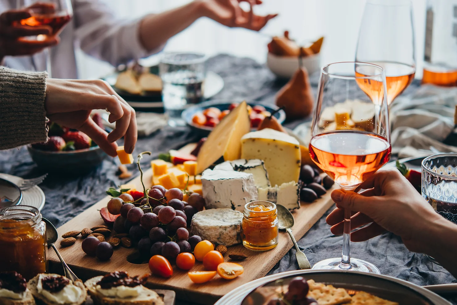 A group of friends shares food and drinks around a Thanksgiving table.