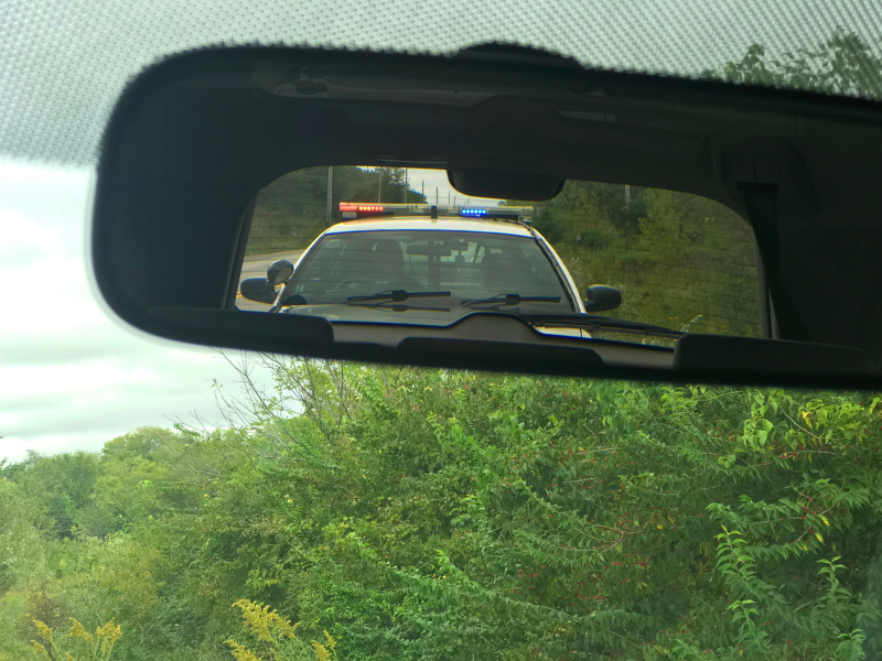 A police car is seen in the rear view mirror of a car. 