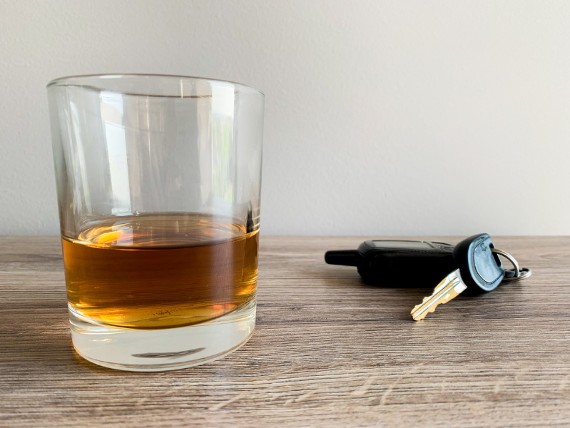 A glass of liquor sits right next to a pair of keys