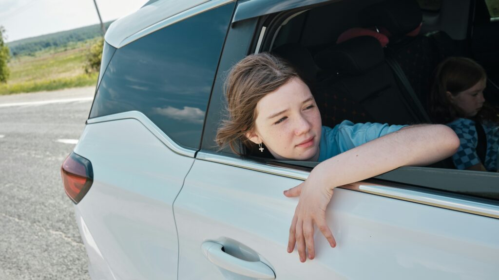 Teen girl leaning out of the car, feeling wind in her hari.